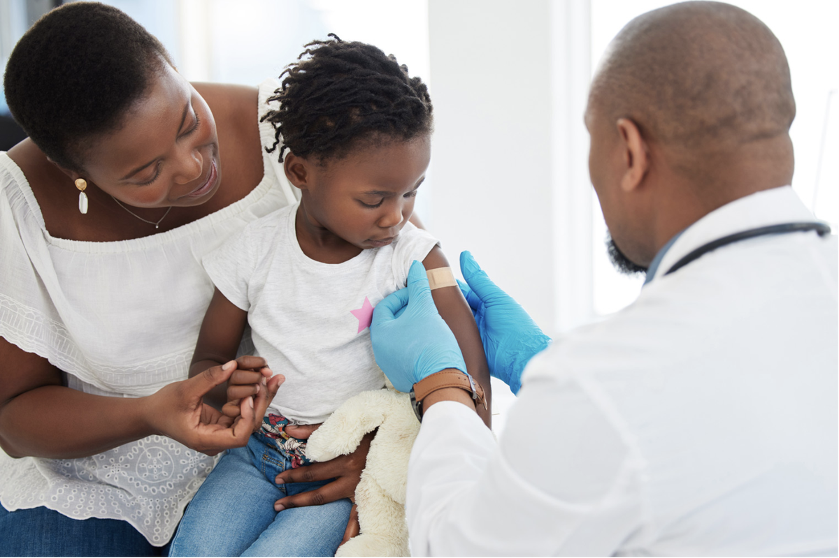 A child receives a vaccination while sitting with her mother.